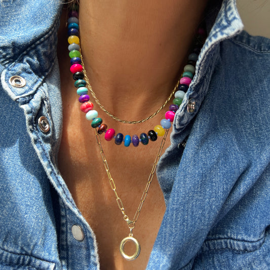 Model wearing a handcrafted gemstone necklace with 8mm opals, jade, turquoise, and more, accented with Czech glass beads and a sterling silver clasp.