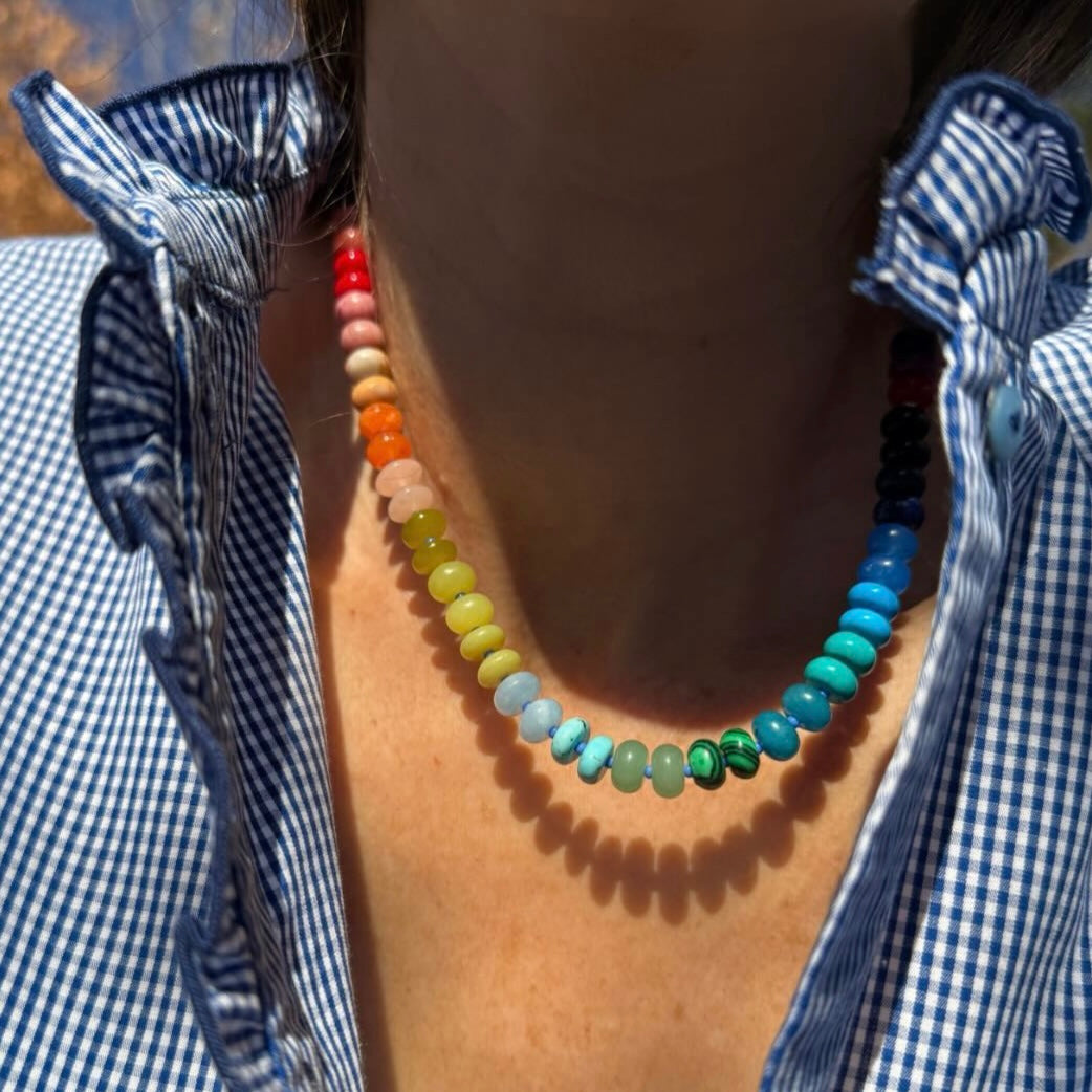 Model wearing a vibrant handcrafted gemstone necklace with 8mm opals, jade, turquoise, and more, accented with Czech glass beads and a sterling silver clasp, styled for layering or standalone elegance.