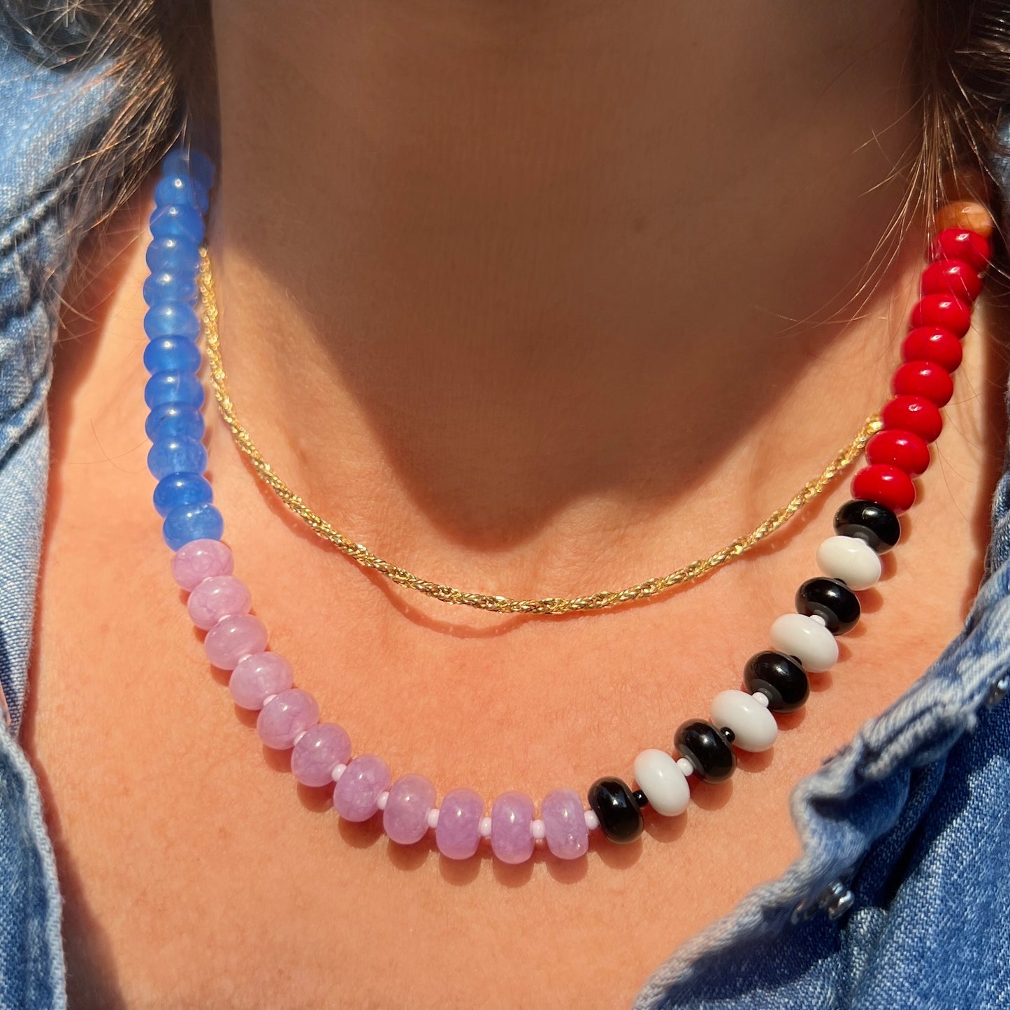 The necklace is styled on a model, showcasing its bold mix of colorful gemstones and premium silver clasp.