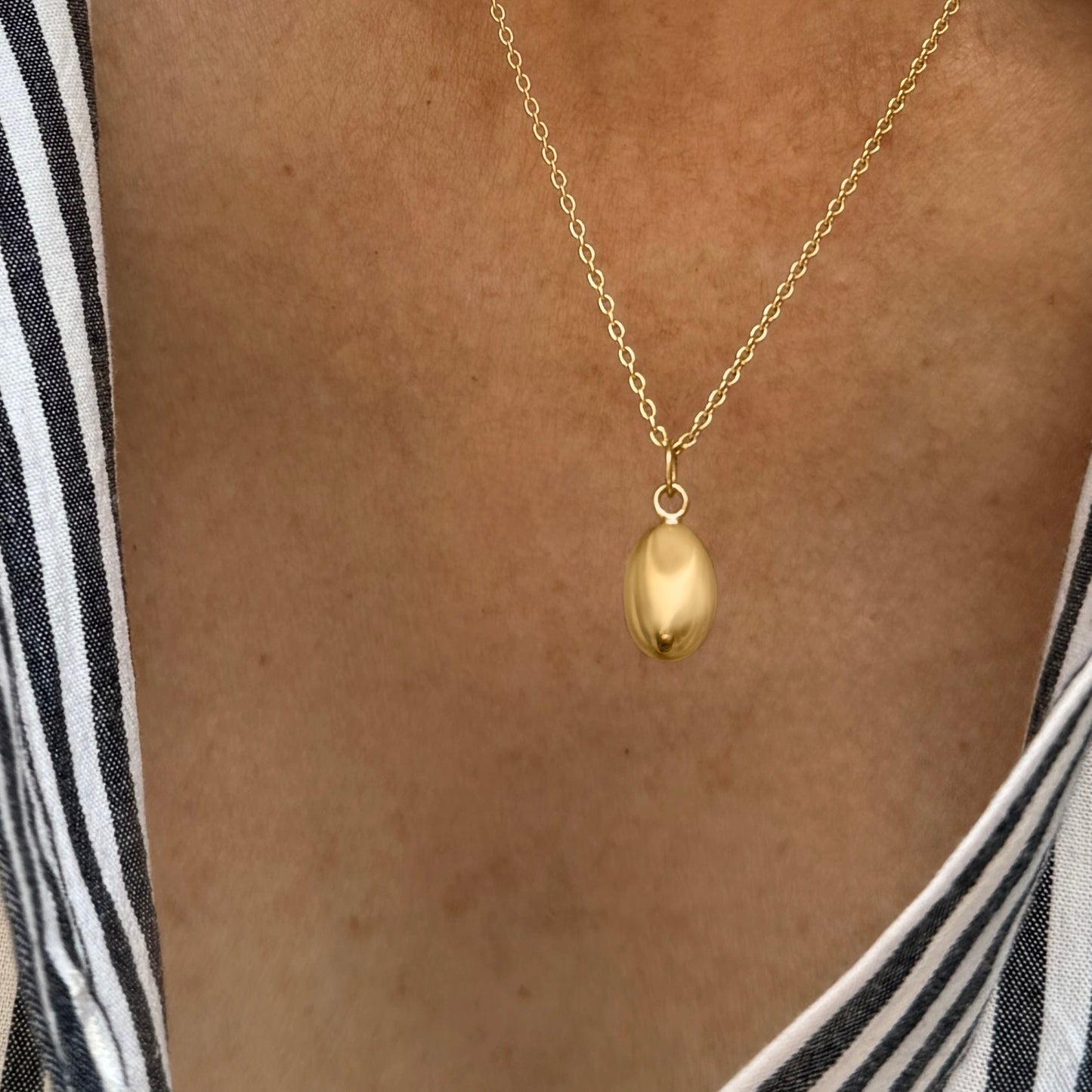 Feminine gold pendant necklace featuring a small breast design