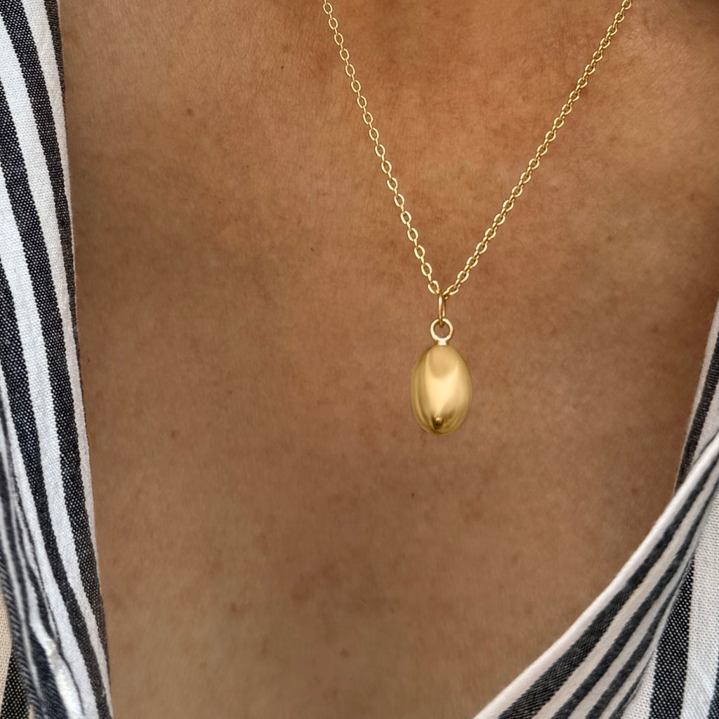 Feminine gold pendant necklace featuring a small breast design