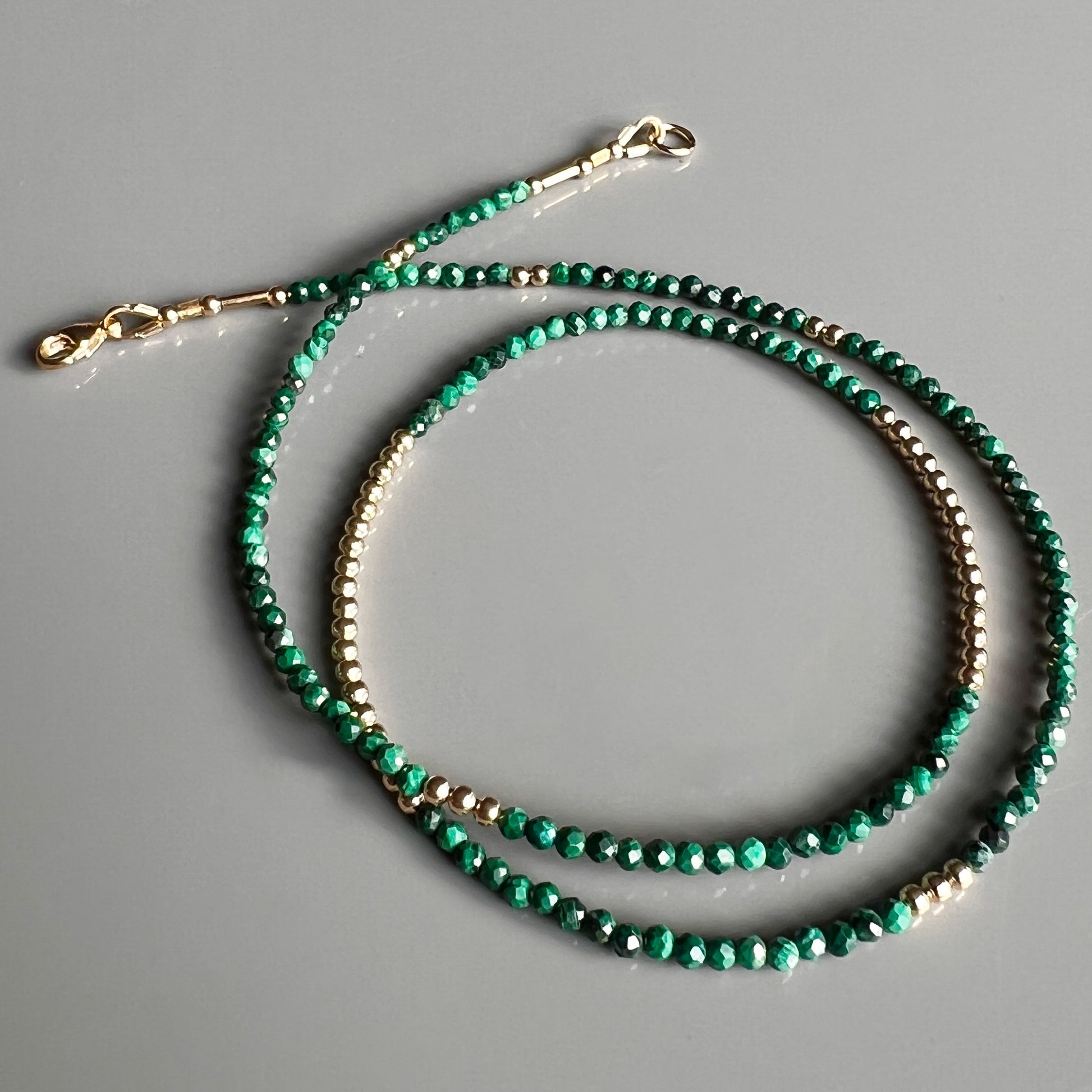 Exquisite faceted malachite gemstone necklace with 14K yellow gold beads, designed for timeless elegance and versatile styling.
