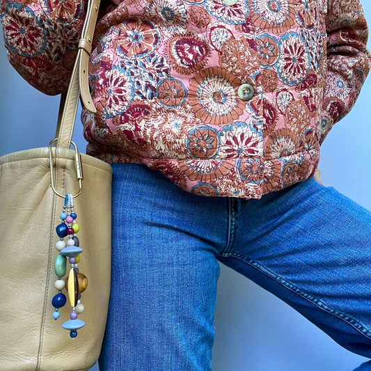 A vintage-inspired bag charm with glass, acrylic, and wooden beads, accented by 14k gold-filled findings.