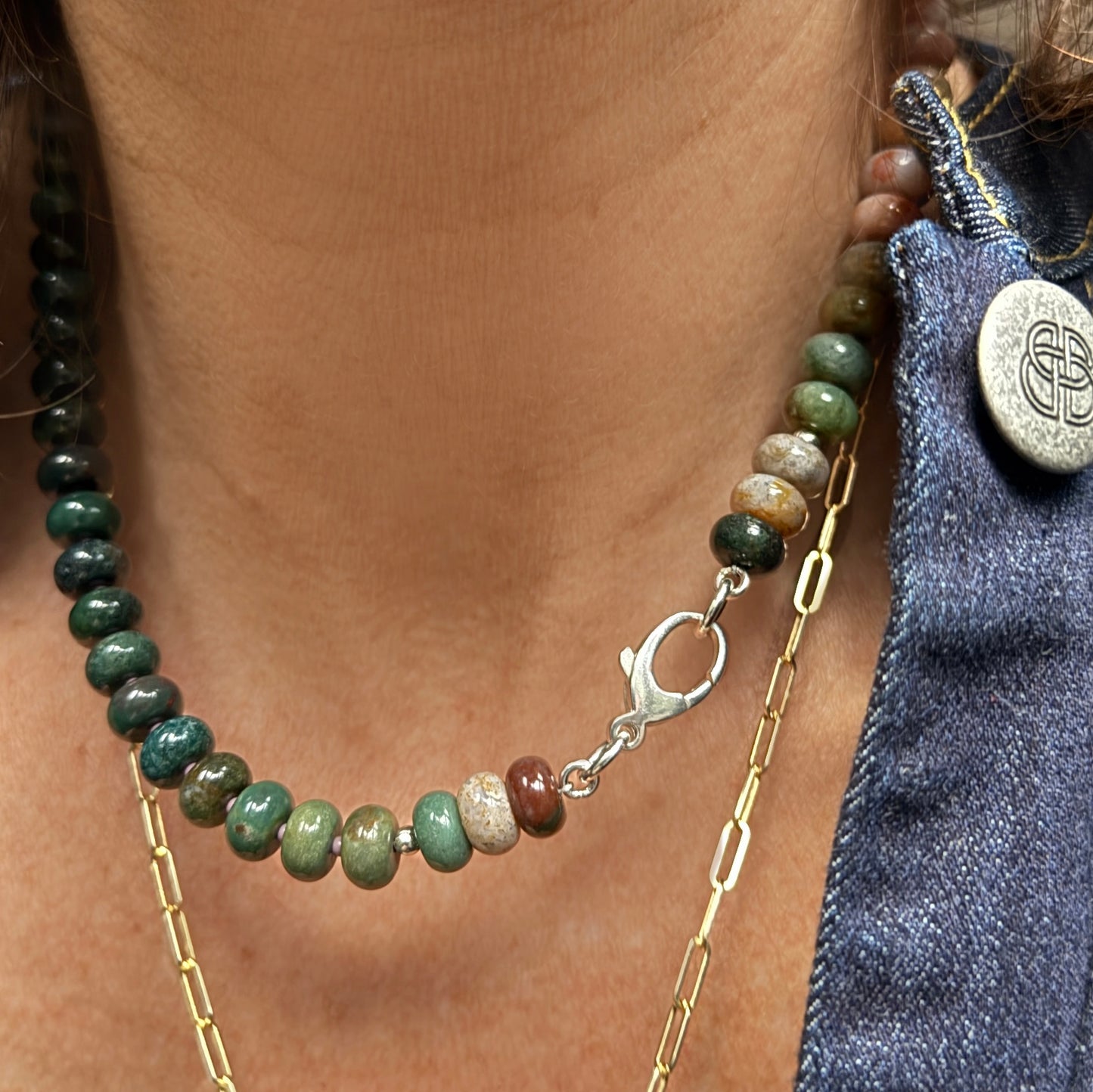A stylish necklace made from glossy, multi-shaded beads reflecting natural light, creating a dynamic play of color.