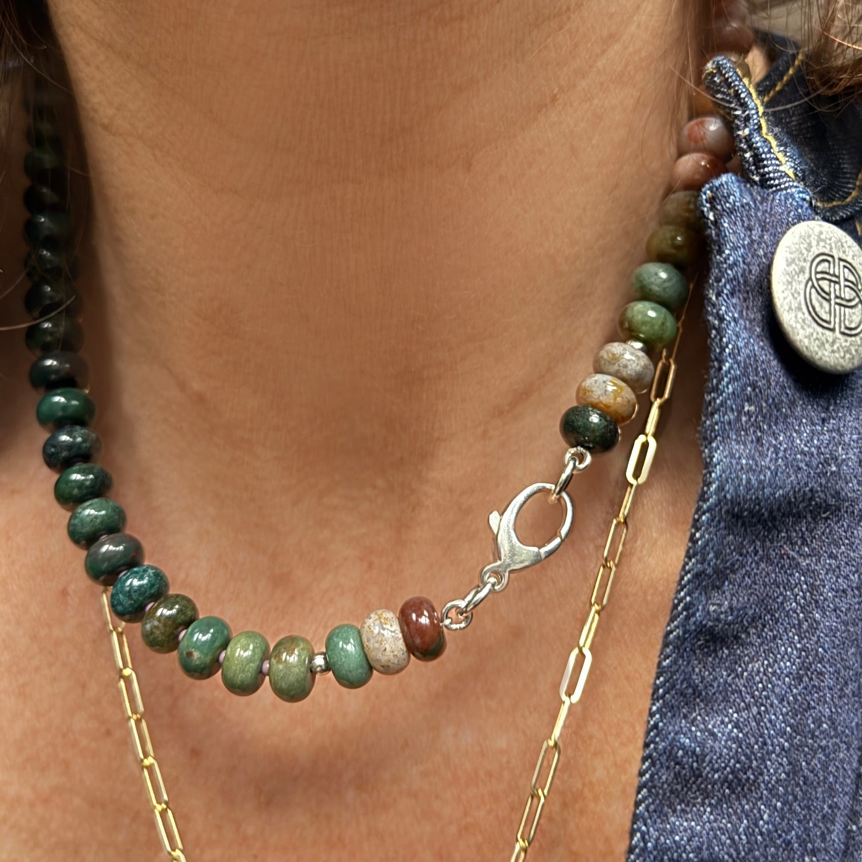 A stylish necklace made from glossy, multi-shaded beads reflecting natural light, creating a dynamic play of color.