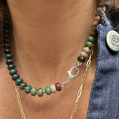 A stylish necklace made from glossy, multi-shaded beads reflecting natural light, creating a dynamic play of color.