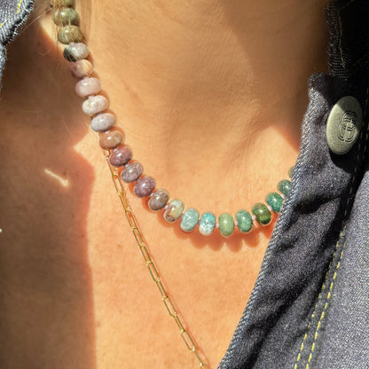 A vibrant beaded necklace showcasing polished stones in a gradient of natural hues, illuminated by soft sunlight.