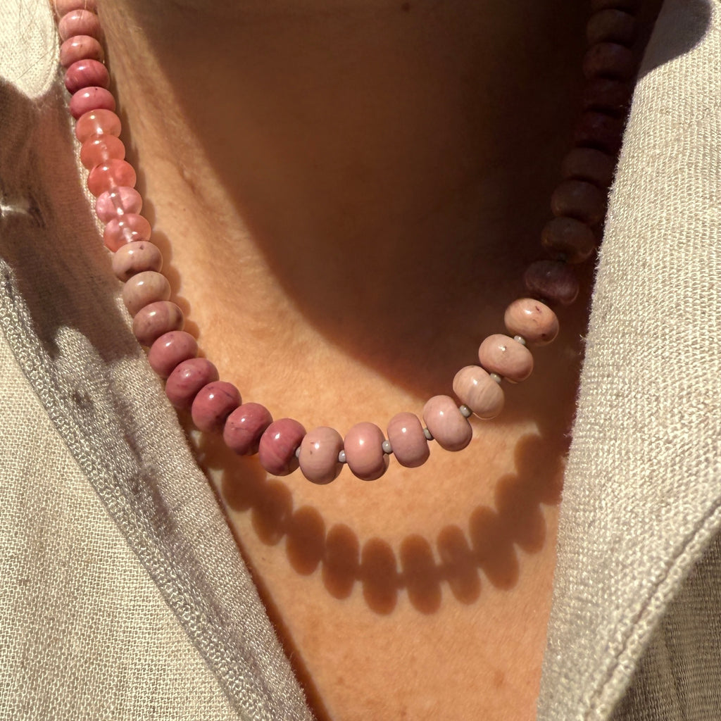 Model wearing a handcrafted gemstone necklace featuring rhodonite, aventurine, and jasper gemstones, accented with Czech glass spacer beads and finished with a 14k gold or sterling silver clasp. A versatile and unique piece, perfect for layering or wearing as a statement accessory