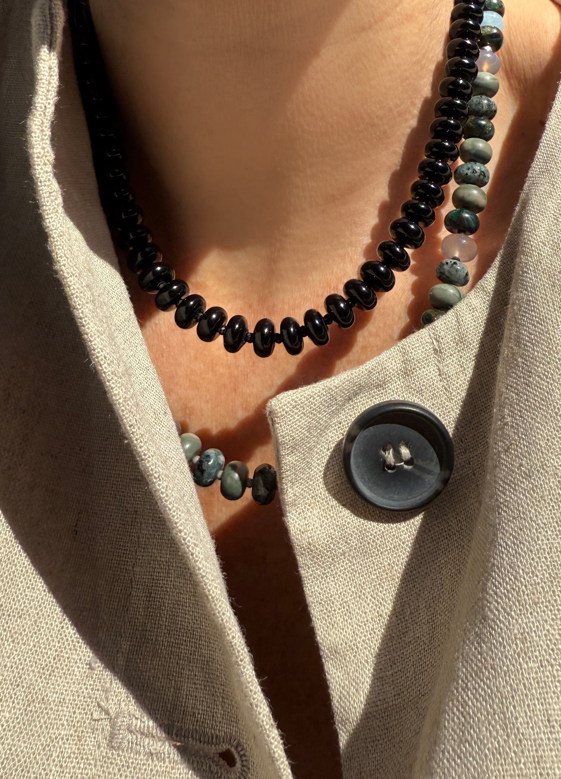 Model wearing a handcrafted gemstone necklace featuring black onyx and jasper gemstones with Czech glass spacer beads.