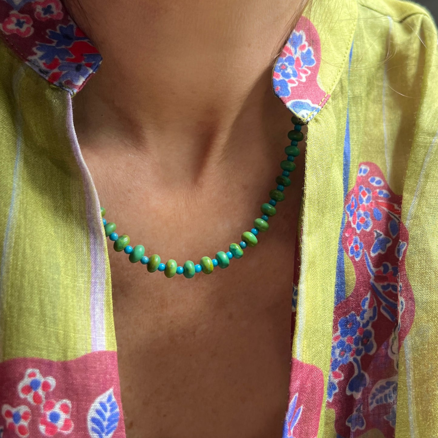 A sleek and colorful necklace with evenly spaced beads in gradient green and blue tones.
