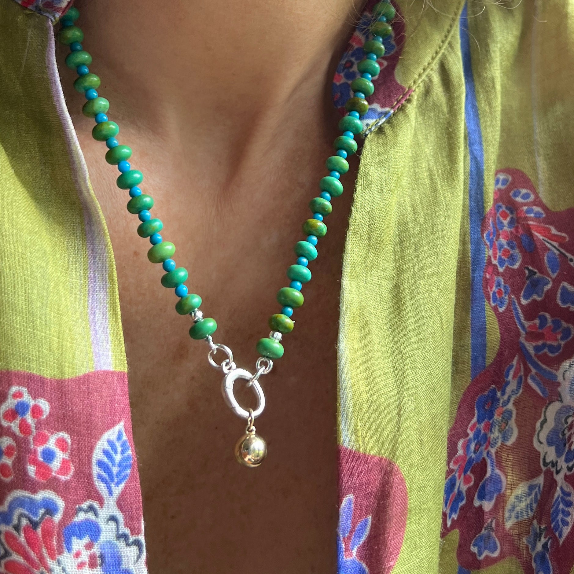 A minimalist beaded necklace in turquoise and green hues, worn by a model for a subtle yet stylish look.