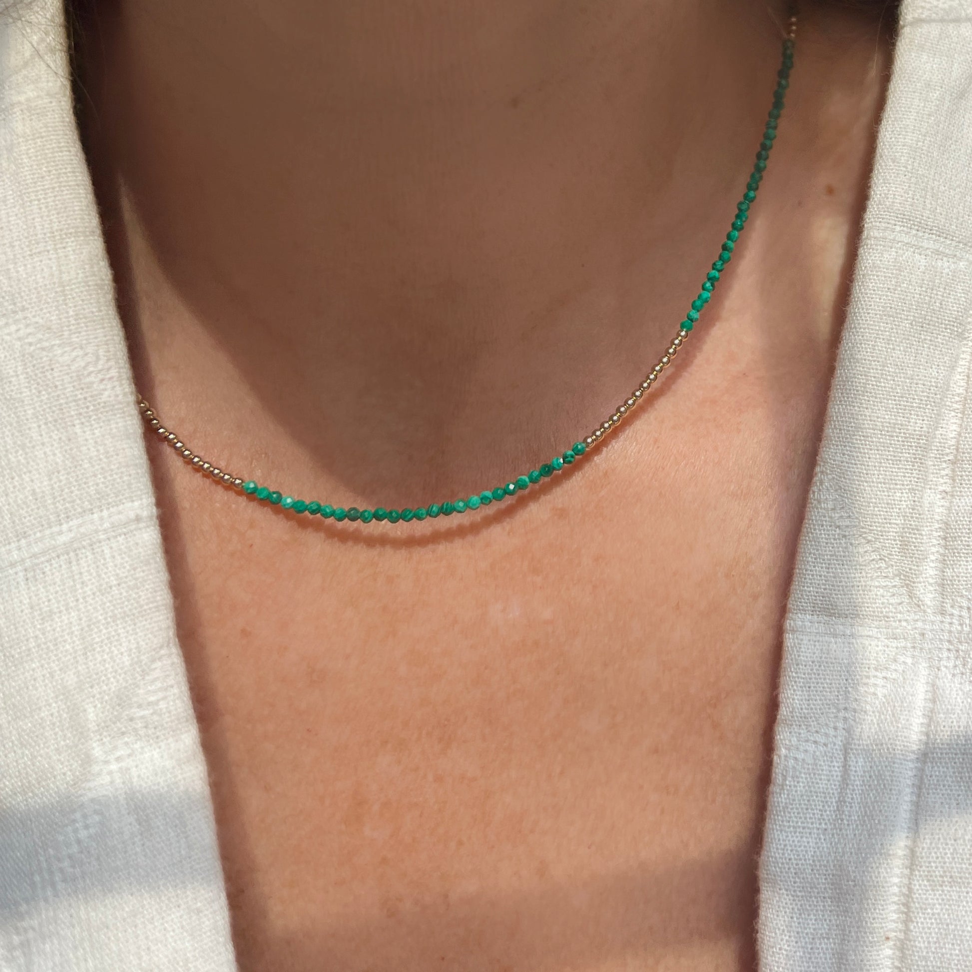Luxurious malachite and 14K gold bead necklace, featuring rich green hues and a secure lobster clasp for a chic, sophisticated look.