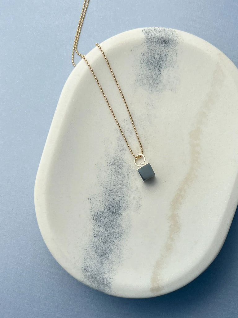 Crafted in solid 14K gold, the Cube Necklace represents resilience and grounding. Its minimalist design is a statement of stability and strength in a chaotic world.