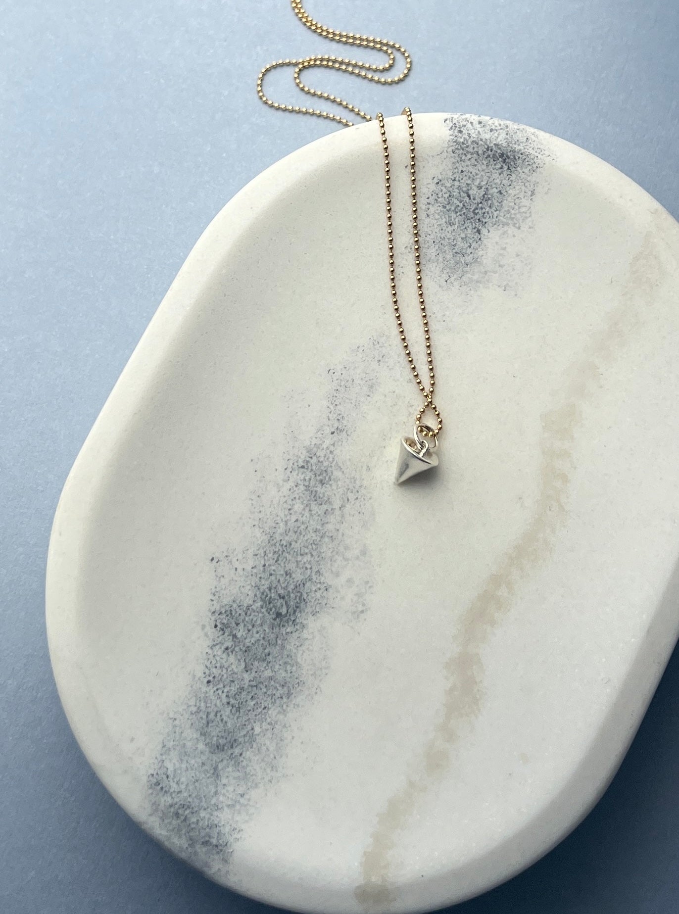 A geometric masterpiece, the Zenith Petite Necklace symbolizes strength, stability, and creativity. Its cone-inspired design embodies the dynamic flow of life, available in premium 14K gold or sterling silver.