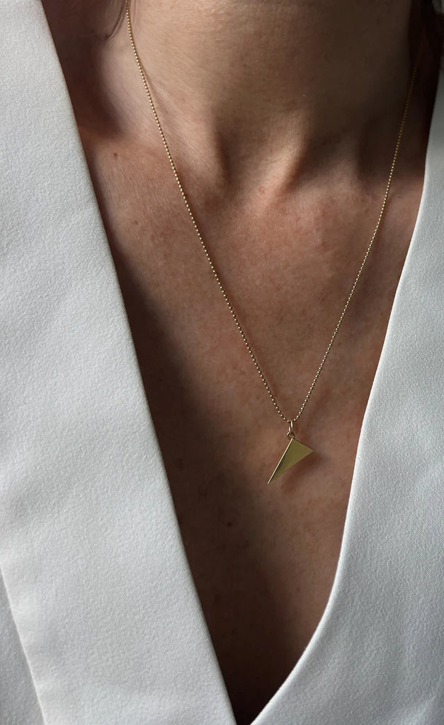 This unique Scalene Triangle Pendant symbolizes embracing imperfection and standing out, available in solid 14K gold or sterling silver for lasting beauty.