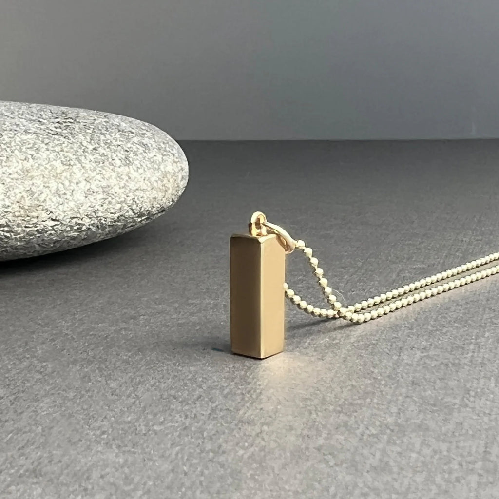 The 14K Gold Rectangle Necklace symbolizes balance and structure, with clean lines and minimalist design, crafted to represent stability and clarity