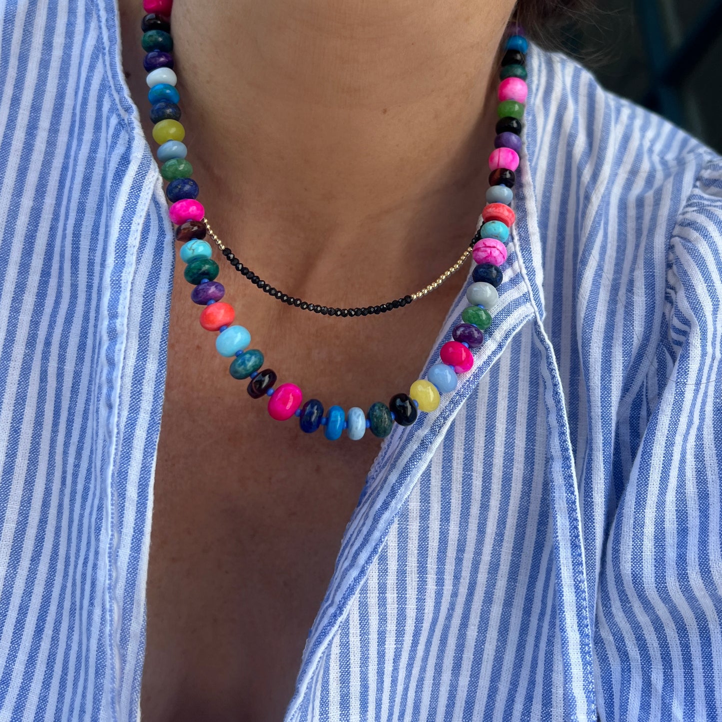 Model wearing a vibrant handcrafted gemstone necklace with 8mm opals, jade, turquoise, and more, accented with Czech glass beads and a sterling silver clasp.