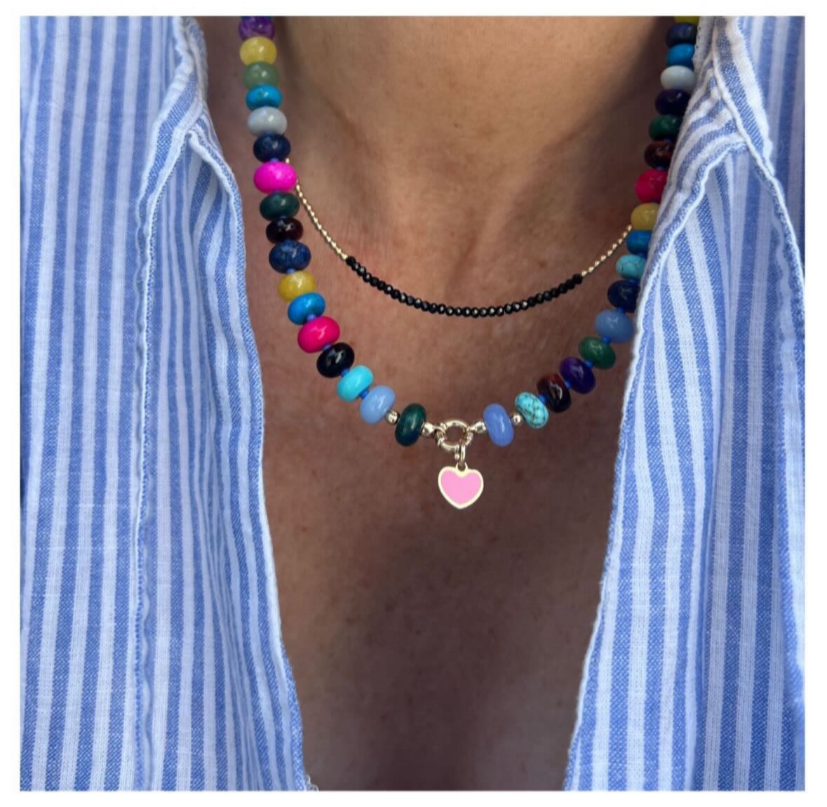 Model wearing a bold handcrafted gemstone necklace with a heart pendant, featuring opals, jade, turquoise, and other stones, with Czech glass beads and a sterling silver clasp.