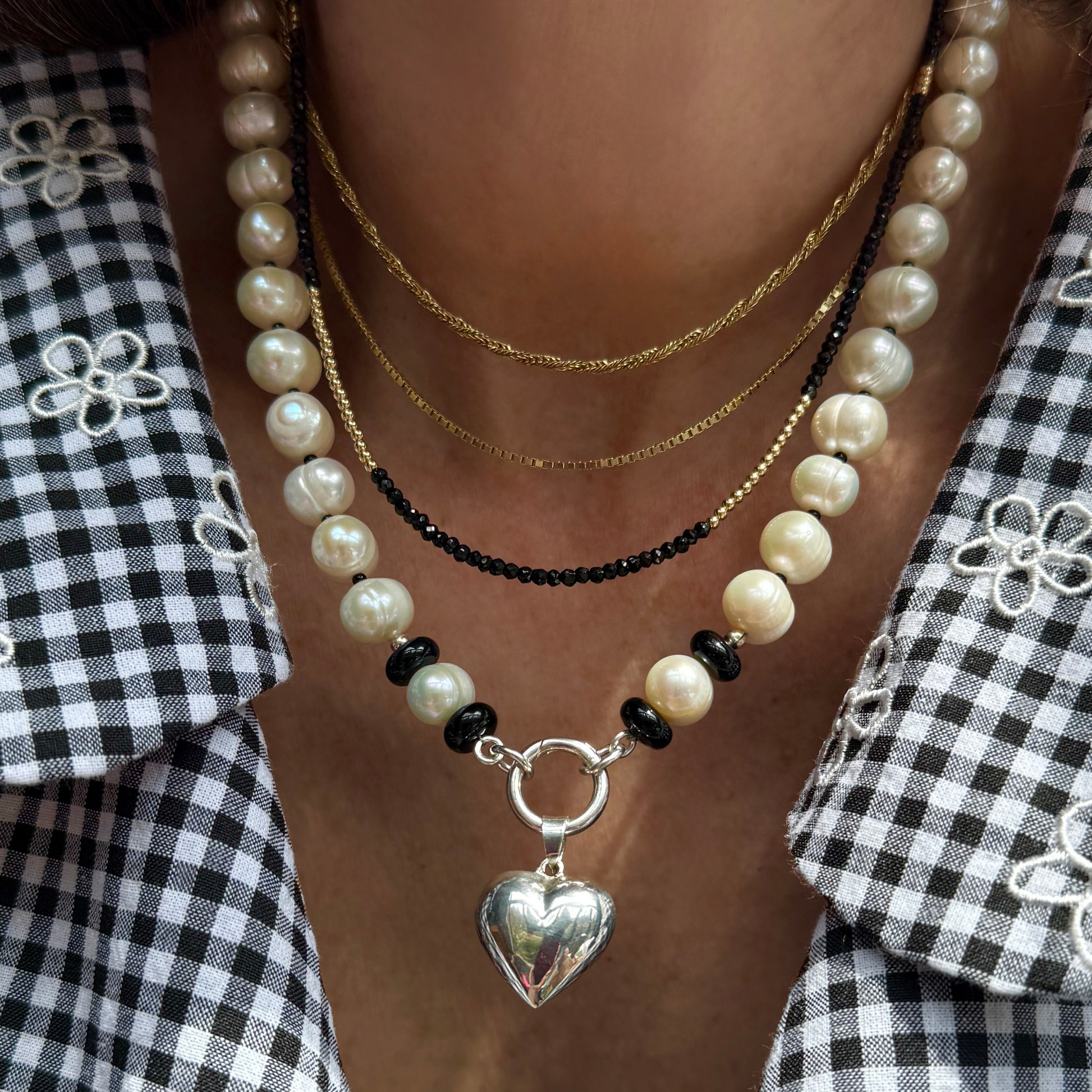 closeup of person wearing pearl necklace with onyx