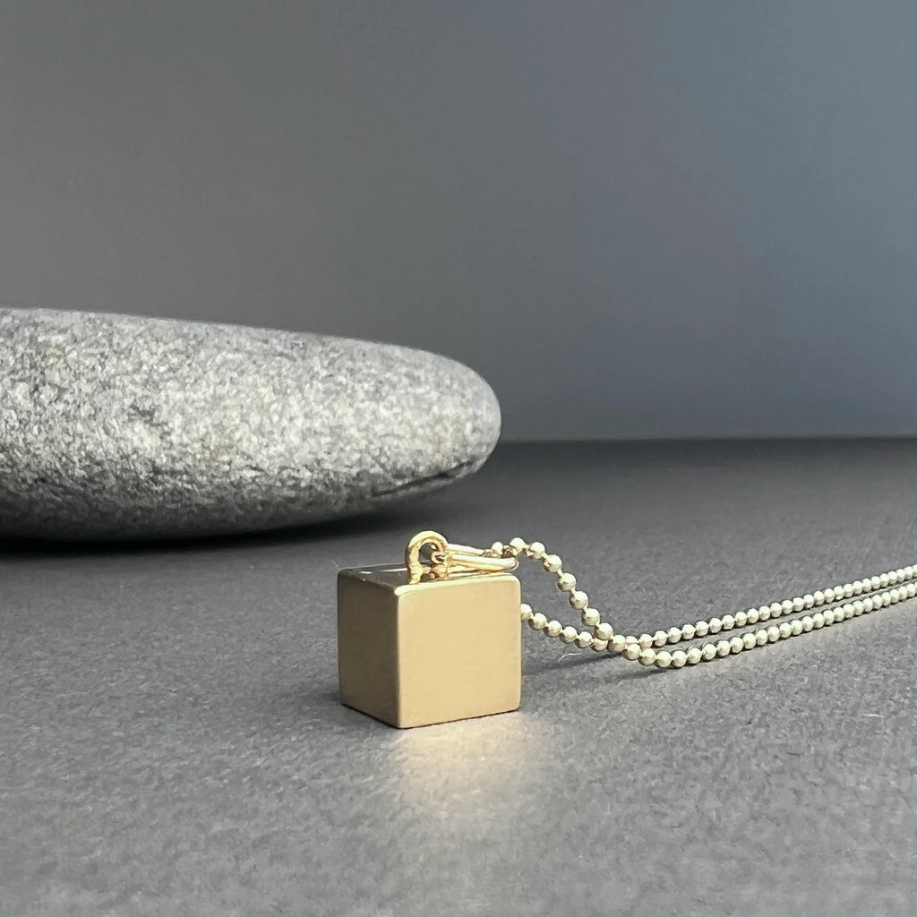 The 14K Gold Cube Necklace, a minimalist design symbolizing stability, resilience, and strength, crafted from solid 14K gold for lasting beauty.