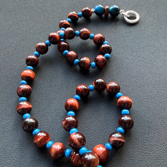 Red-brown tiger's eye and bright blue beads with a silver clasp, coiled flat lay, by SOLO Jewelry